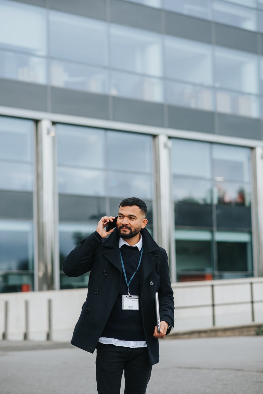 ethnic manager talking on smartphone on city street